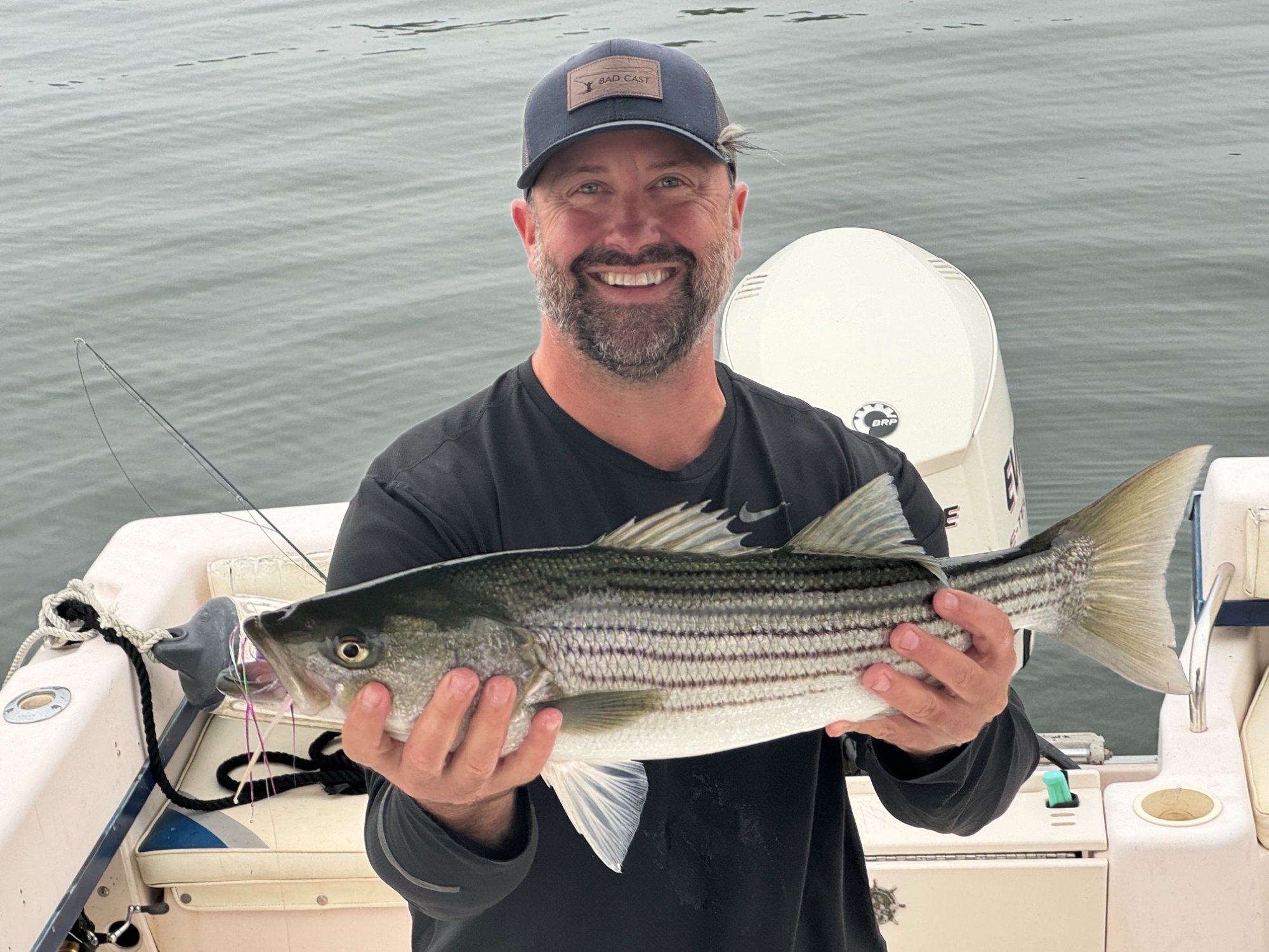 Captain Drew Renda holding a striped bass on F/V Bad Cast