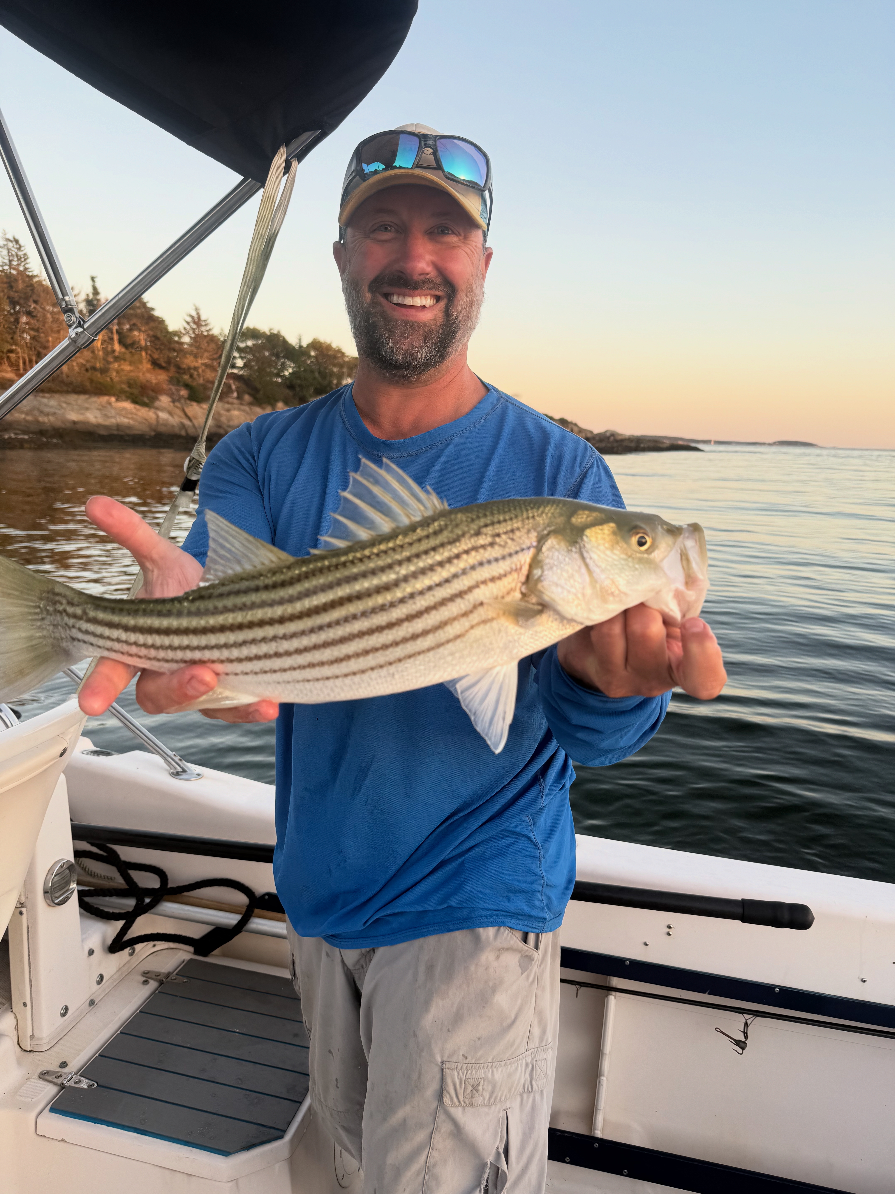 Captain Drew in blue shirt holding a fish on F/V Bad Cast